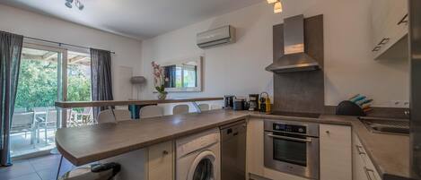 A modern kitchen with a built-in washing machine, oven, and a large window.