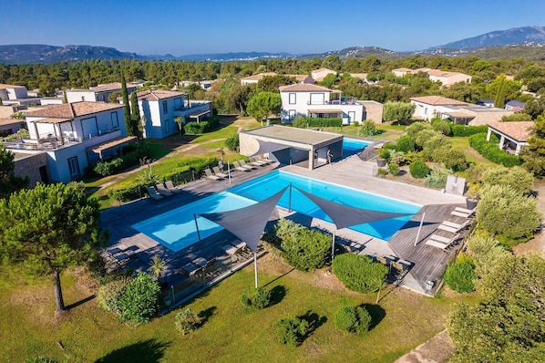 An aerial view of a residential area with a swimming pool, surrounded by houses and greenery. - Lecci Apartment With Outdoor Pool (Lecci)