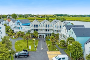 A residential building with a central entrance, multiple balconies, and a surrounding green landscape. - Courseulles Family Apartment for 6 (Courseulles-sur-Mer)