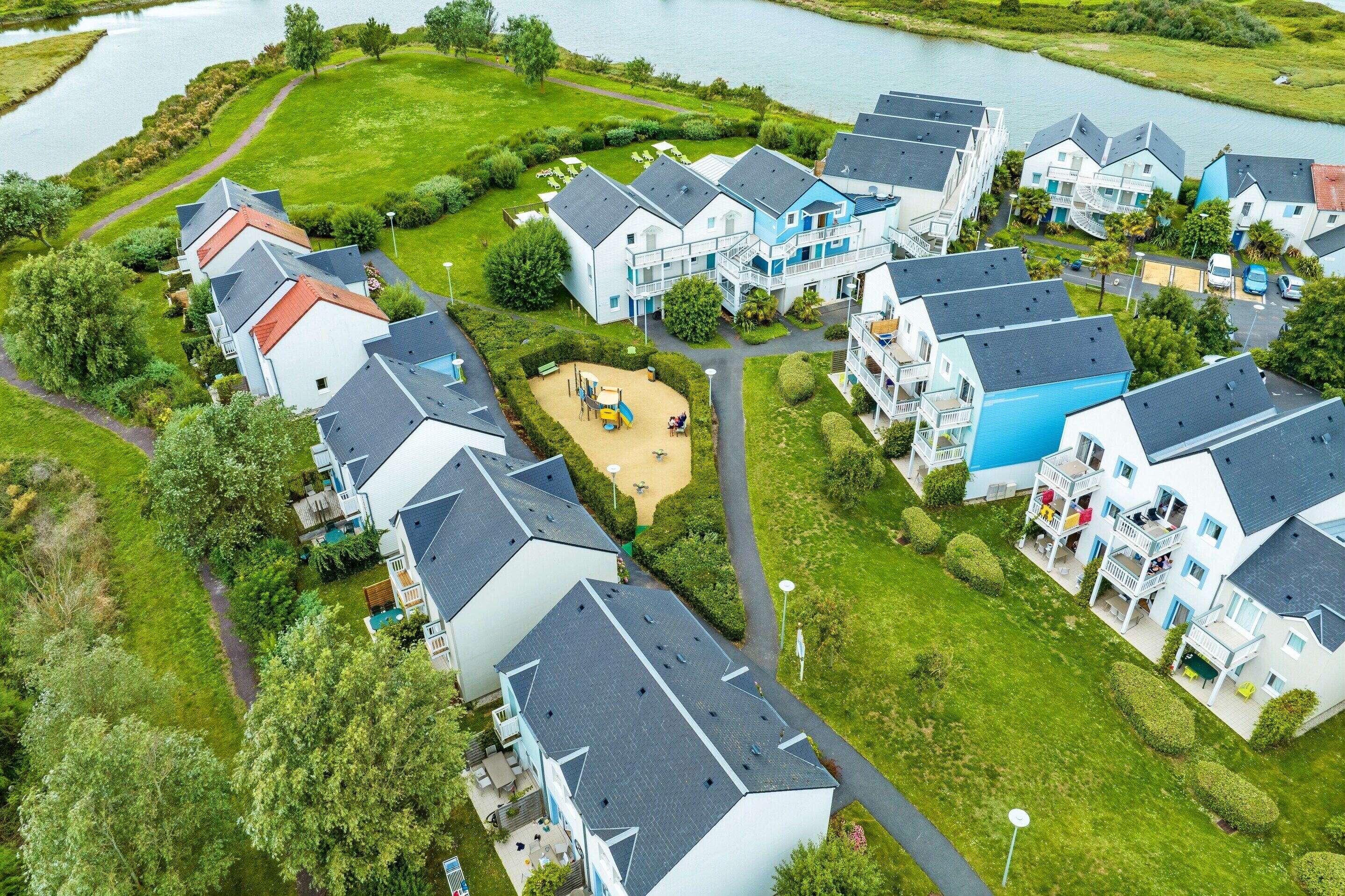 Et boligområde med huse, en legeplads og et vandareal.