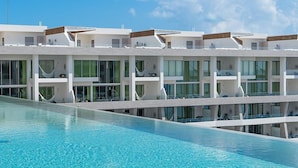 A modern hotel with a pool, multiple balconies, and large windows. - Beautiful location offers  white-sand beaches, gourmet dining and  infinity pool (Cancun)