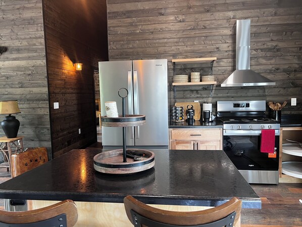 A modern kitchen with a central island, stainless steel appliances, and wooden accents.