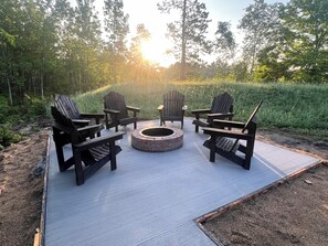 A circular fire pit with four Adirondack chairs arranged around it on a paved patio. - Lost Lake Moonlight Cabin- New build, Lake Front 2BD 2Bath - ADA - hot tub (Bagley)
