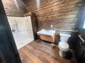 Une salle de bain avec un mur en bois, une douche, un lavabo et des toilettes.