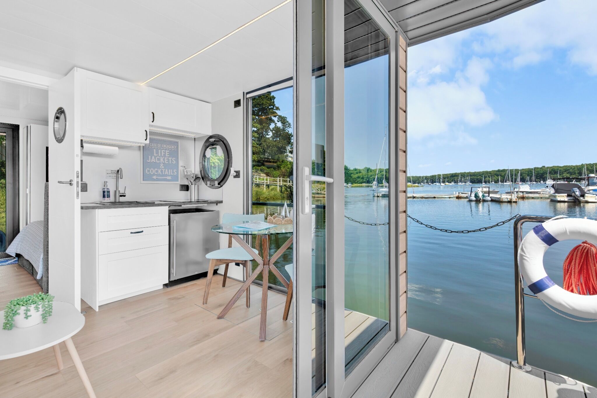 Een moderne keuken met uitzicht op een jachthaven, een eetgedeelte met een tafel en stoelen, en een reddingsboei op het dek.