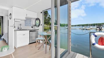 Een moderne keuken met uitzicht op een jachthaven, een eetgedeelte met een tafel en stoelen, en een reddingsboei op het dek.