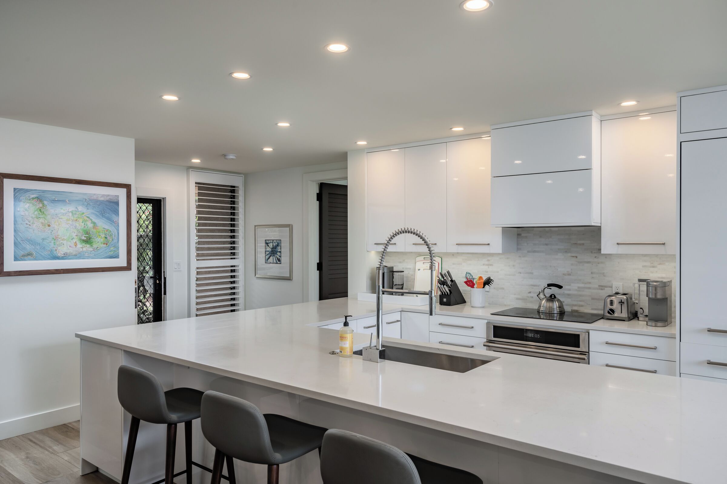 Une cuisine moderne dotée d’un grand îlot central, de meubles blancs et d’appareils électroménagers en acier inoxydable.