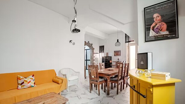 Una sala de estar moderna con un sofá, una mesa de centro de madera, una mesa de comedor, sillas y un armario amarillo.