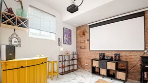 Una habitación con una barra amarilla, un proyector, una pizarra y una pared de ladrillo.