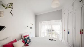 Un dormitorio con una cama grande, un armario y un balcón con vistas.