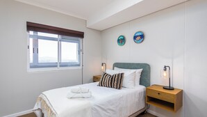 Een slaapkamer met een bed, nachtkastjes, een raam en wanddecoraties.