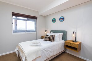Ein Schlafzimmer mit einem Bett, Nachttischen, einem Fenster und Wanddekorationen.