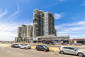 A multi-story hotel with a modern design, featuring balconies on each floor, a central atrium, and a parking lot with several cars. - Blu Horizon
Modern Beachfront 3BR with Epic Table Mountain Views (Cape Town)
