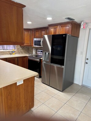 A kitchen with wooden cabinets, stainless steel appliances, and a white door.