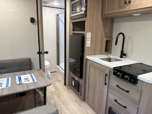A compact RV kitchen with a sink, stove, and a dining area with a table.