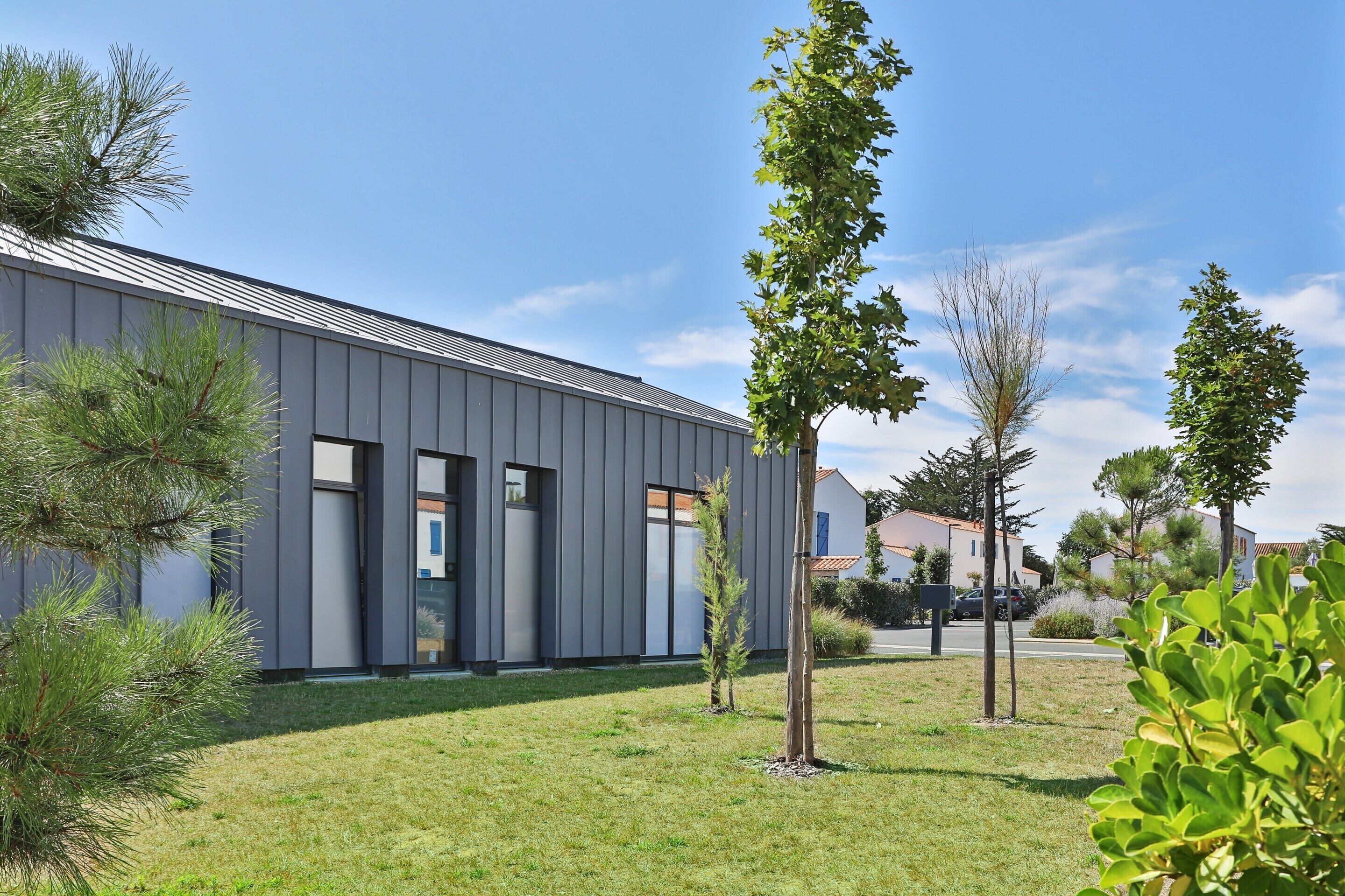 A modern building with a flat roof, a well-maintained lawn, and a few young trees.