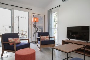 A modern living room with a TV, two sofas, a coffee table, and a large window. - Picturesque 6-person Duplex Oasis (Les Sables-d'Olonne)