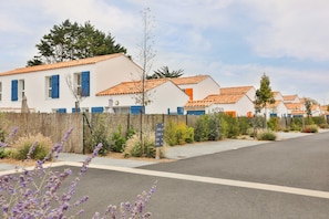 A row of white buildings with orange roofs, a wooden fence, and a signpost. - Picturesque 6-person Duplex Oasis (Les Sables-d'Olonne)