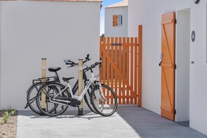 A bicycle parked in front of a white building with a wooden gate and a numbered door. - Picturesque 6-person Duplex Oasis (Les Sables-d'Olonne)