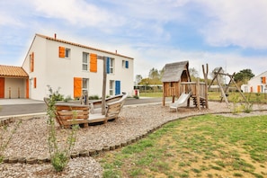 Un barrio residencial con una casa, un bote de madera y un parque infantil.