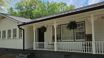 A two-story house with a porch, a front door, and a small front yard.