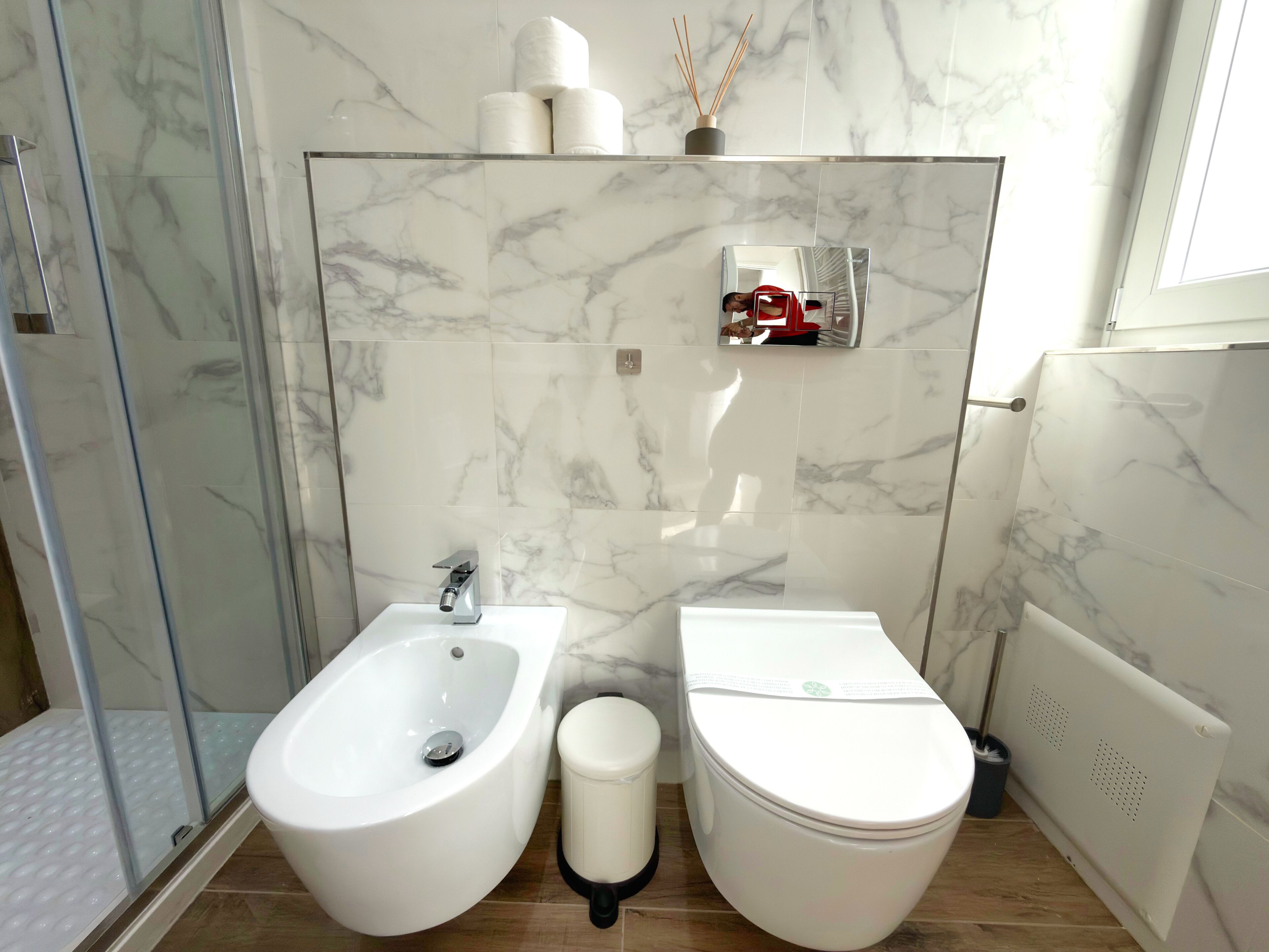 A bathroom with a bidet, toilet, and a shower area.