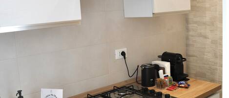 Una cocina moderna con estufa a gas, horno y armarios blancos.
