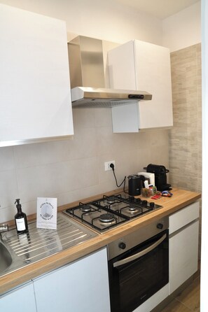 A modern kitchen with a gas stove, oven, and white cabinets. - Termoli Station (Termoli)
