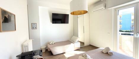 Habitación de hotel con dos camas, televisión, cafetera y vistas al exterior.