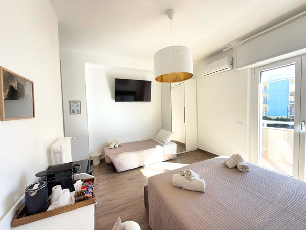 A hotel room with two beds, a TV, a coffee machine, and a view of the outside.