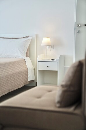 Ett hotellrum med en säng, ett nattduksbord med en lampa, en stol och en dörr.