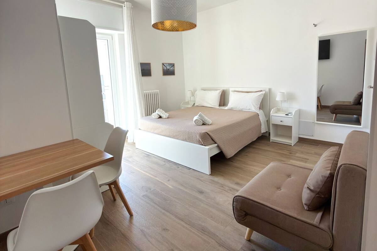 A modern bedroom with a bed, bedside tables, a desk, and a chair.