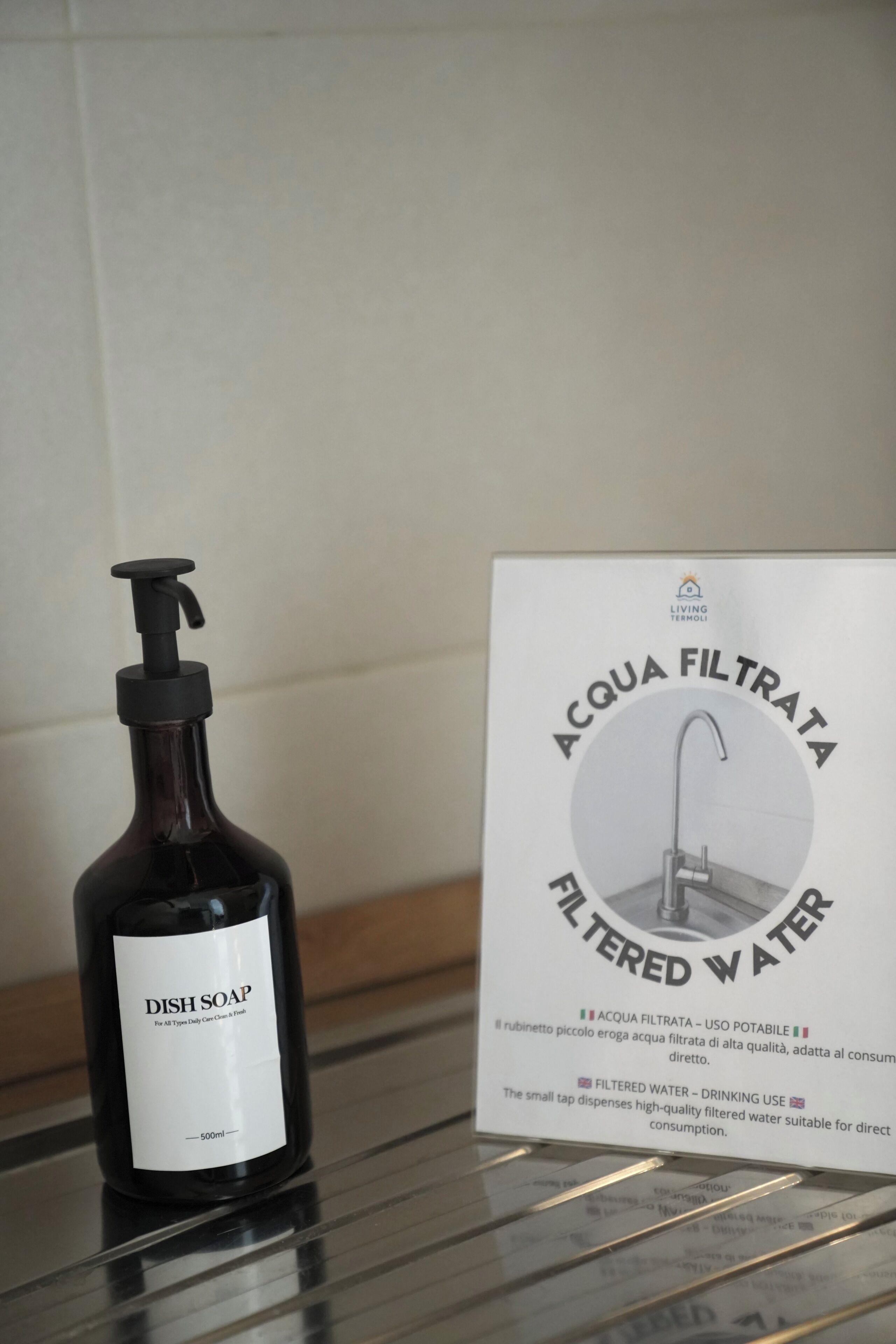 A bottle of dish soap and a sign for filtered water.