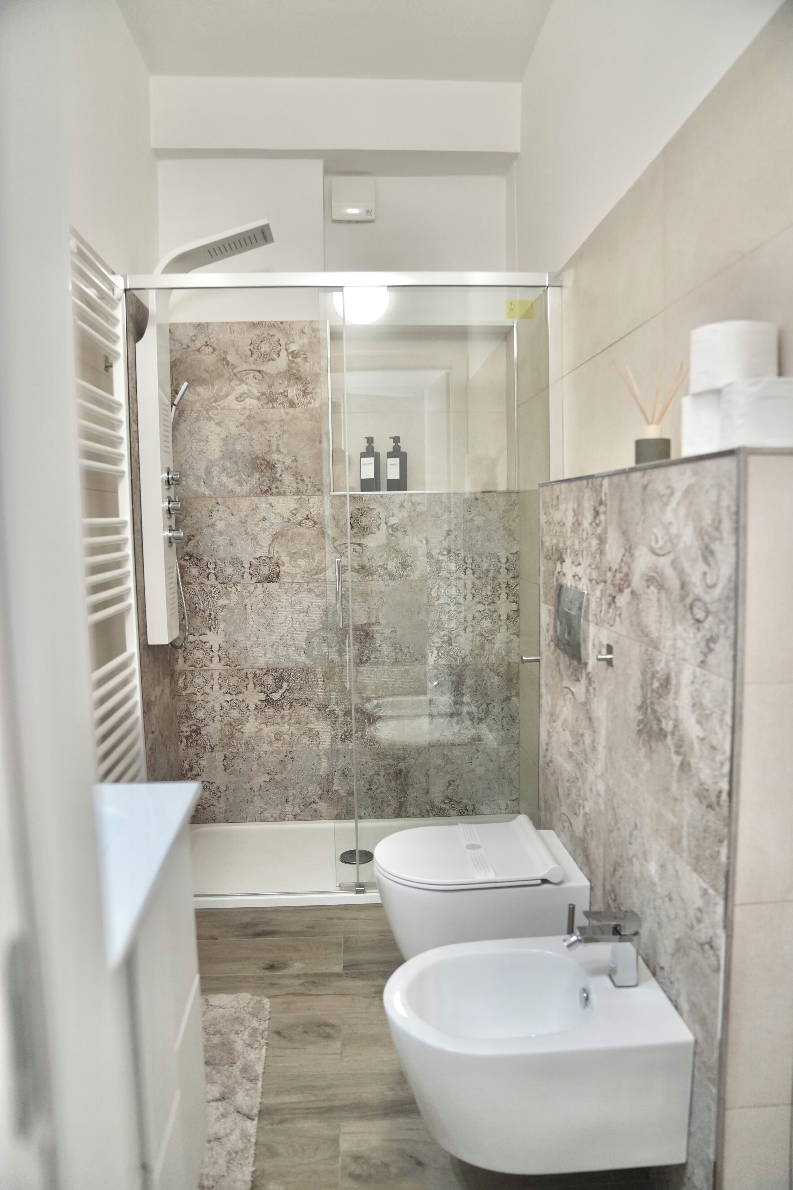A modern bathroom with a glass-enclosed shower, a white sink, and a toilet.