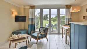 A room with a television, a dining table, a sofa, and a chair with a cushion. - Holiday House Near Lake & Sea (Talmont-Saint-Hilaire)