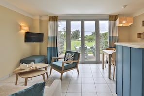 A room with a television, a dining table, a sofa, and a chair with a cushion. - Holiday House Near Lake & Sea (Talmont-Saint-Hilaire)