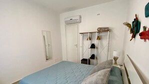 Une chambre à coucher comprenant un lit, une armoire, un miroir et un climatiseur fixé au mur.