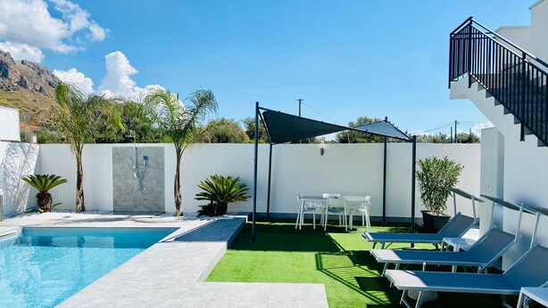 Une piscine dotée d’une terrasse ensoleillée, de chaises longues et d’un escalier.
