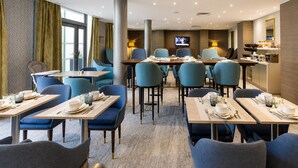 A hotel dining area with tables, chairs, and a television screen. - Picturesque Deauville Apartment for 6 (Deauville)