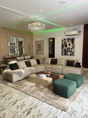 Ein modernes Wohnzimmer mit einem Ecksofa, einem Couchtisch und einer Pendelleuchte.