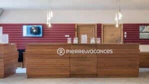 Una recepción con logotipo, un televisor montado y un panel de pared de madera.