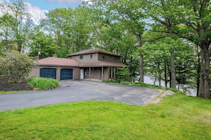 A two-story house with a garage, surrounded by trees and a driveway.