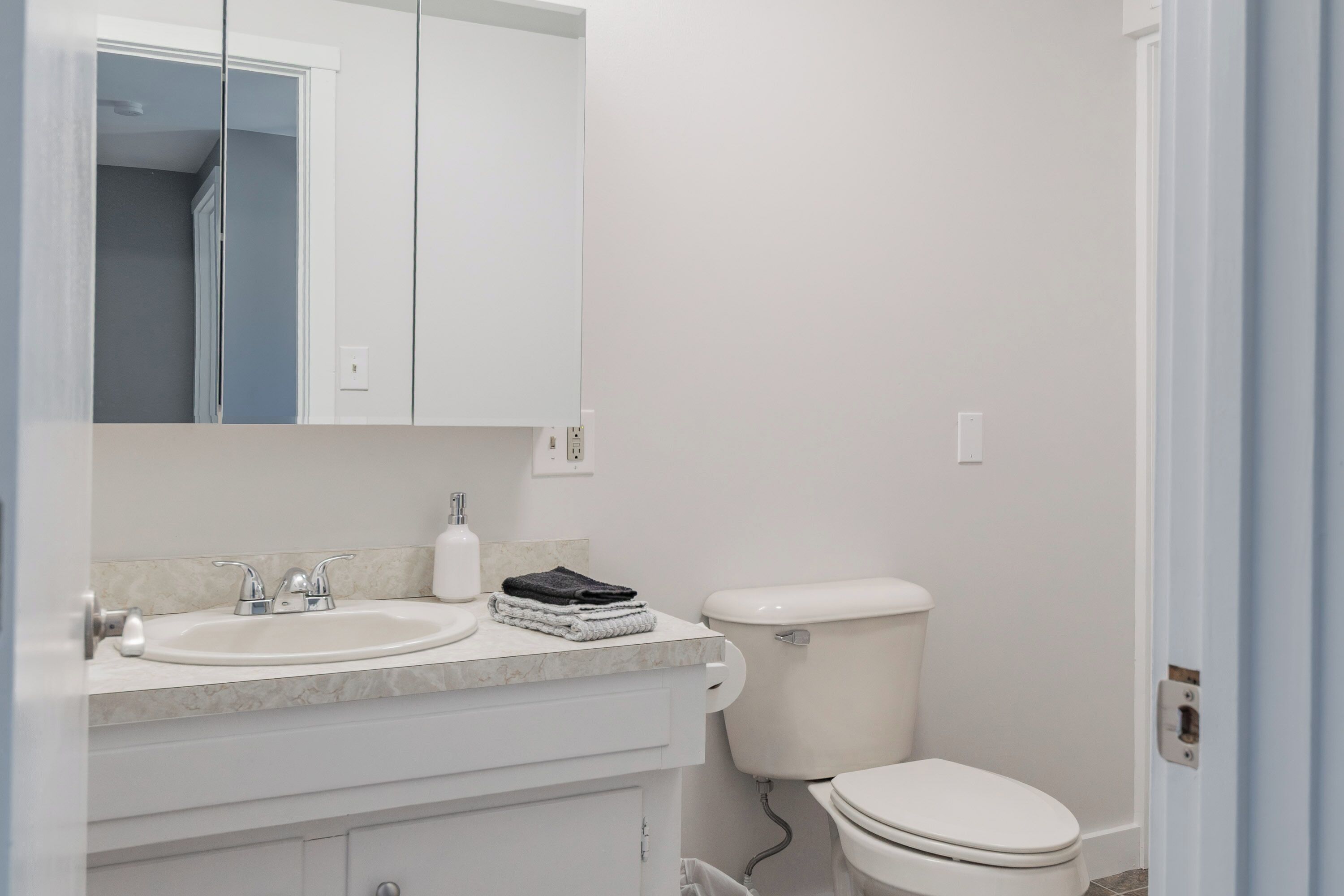 Un baño con lavamanos blanco, espejo e inodoro.