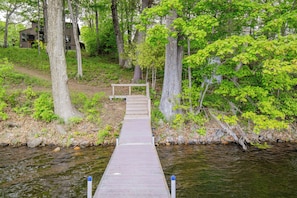 A wooden dock leading to a house surrounded by trees.