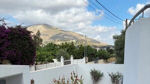 Um pátio com parede branca, um banco de pedra e vista para uma montanha.