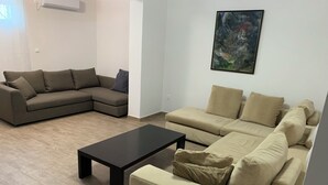 Un soggiorno con un divano componibile, un tavolino da caffè e un quadro appeso al muro.