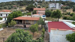 Un quartiere residenziale con case, alcune con tetti in tegole rosse, circondato da vegetazione e colline.