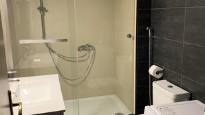 Un bagno moderno con doccia vetrata, un water e una lavatrice.