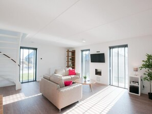 A modern living room with a sofa, a coffee table, and a TV. - Villa in Tholen With Private Garden (Tholen)