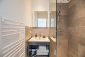 A bathroom with a glass-enclosed shower, a white sink, a mirror above the sink, and a towel rack. - Corsica Haven With Garden (Lecci)
